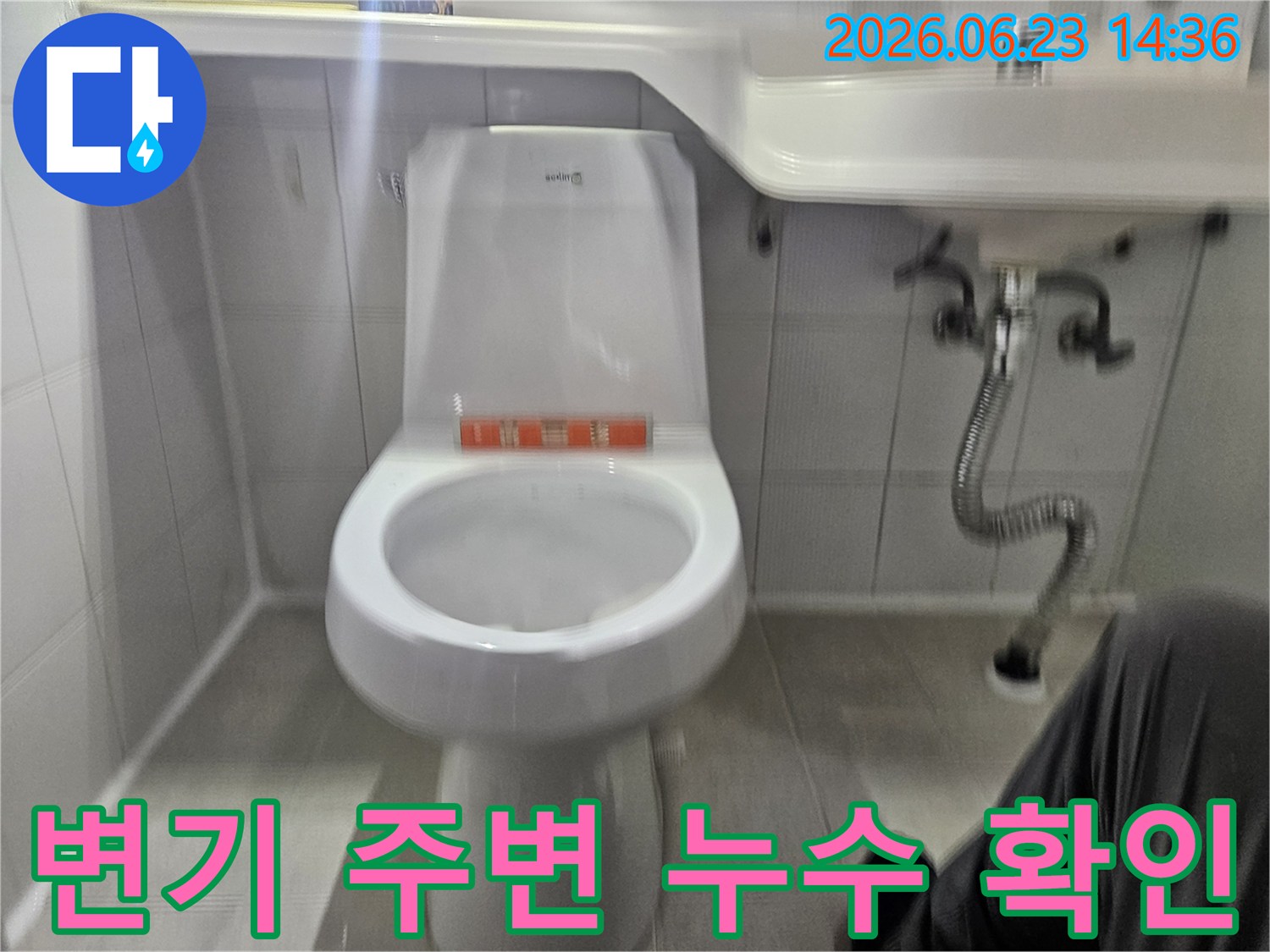 이 사진은 화장실 변기 주변에서 발생한 누수 현상을-전문가가 면밀히 검토하고 있는 모습을 보여줍니다.