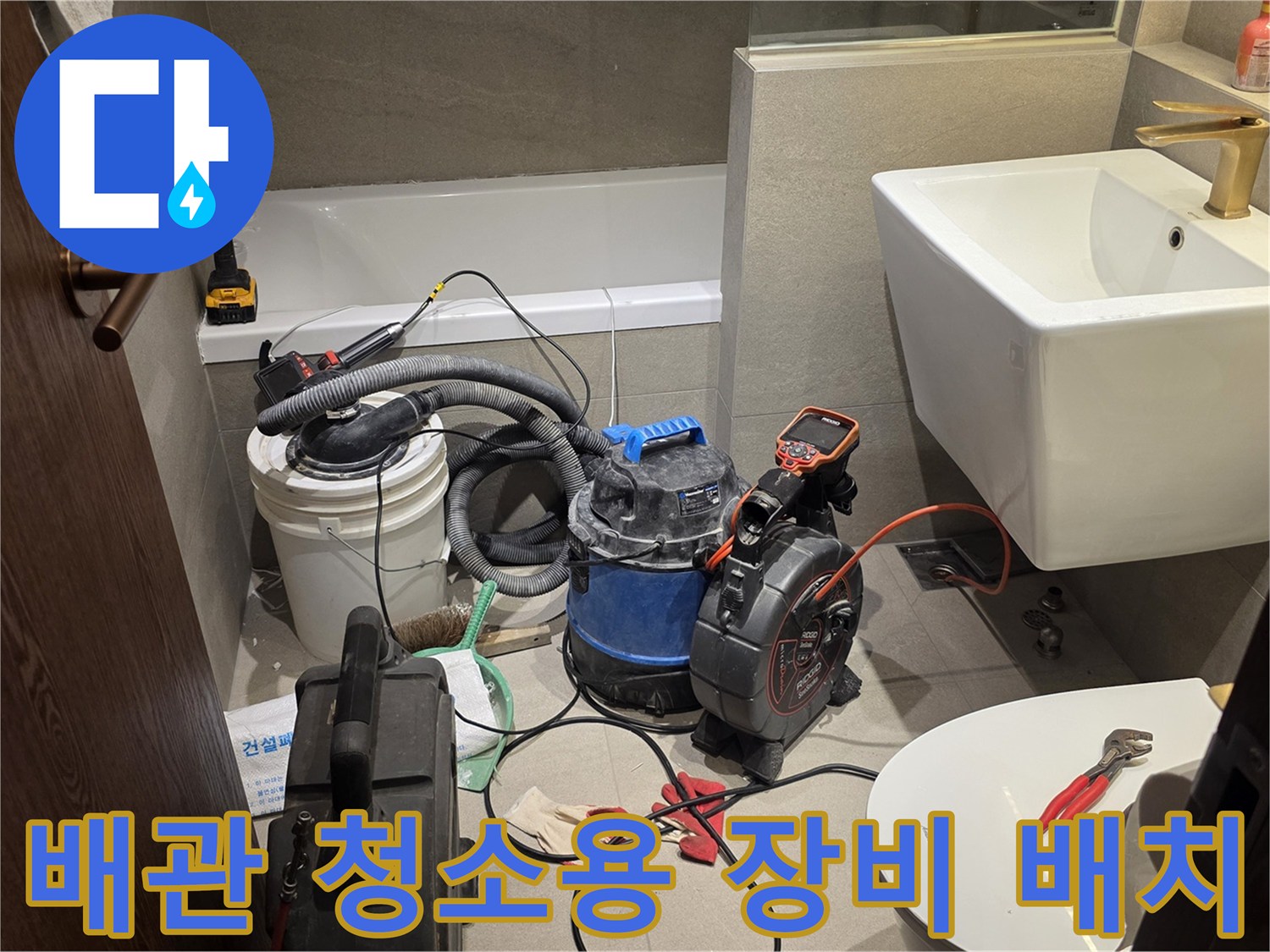 세면대 아래 작업 공간에 놓인 산업용 청소기와 펜치 및 드라이버