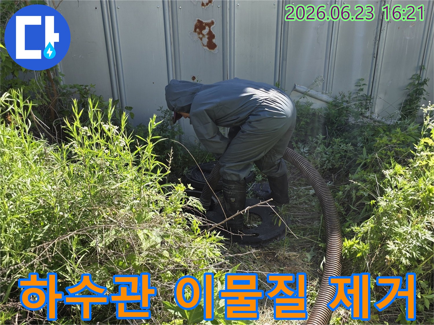전문 작업자가 야외 하수관의 이물질을 제거하기 위해 흡입 장비를 사용하는 모습