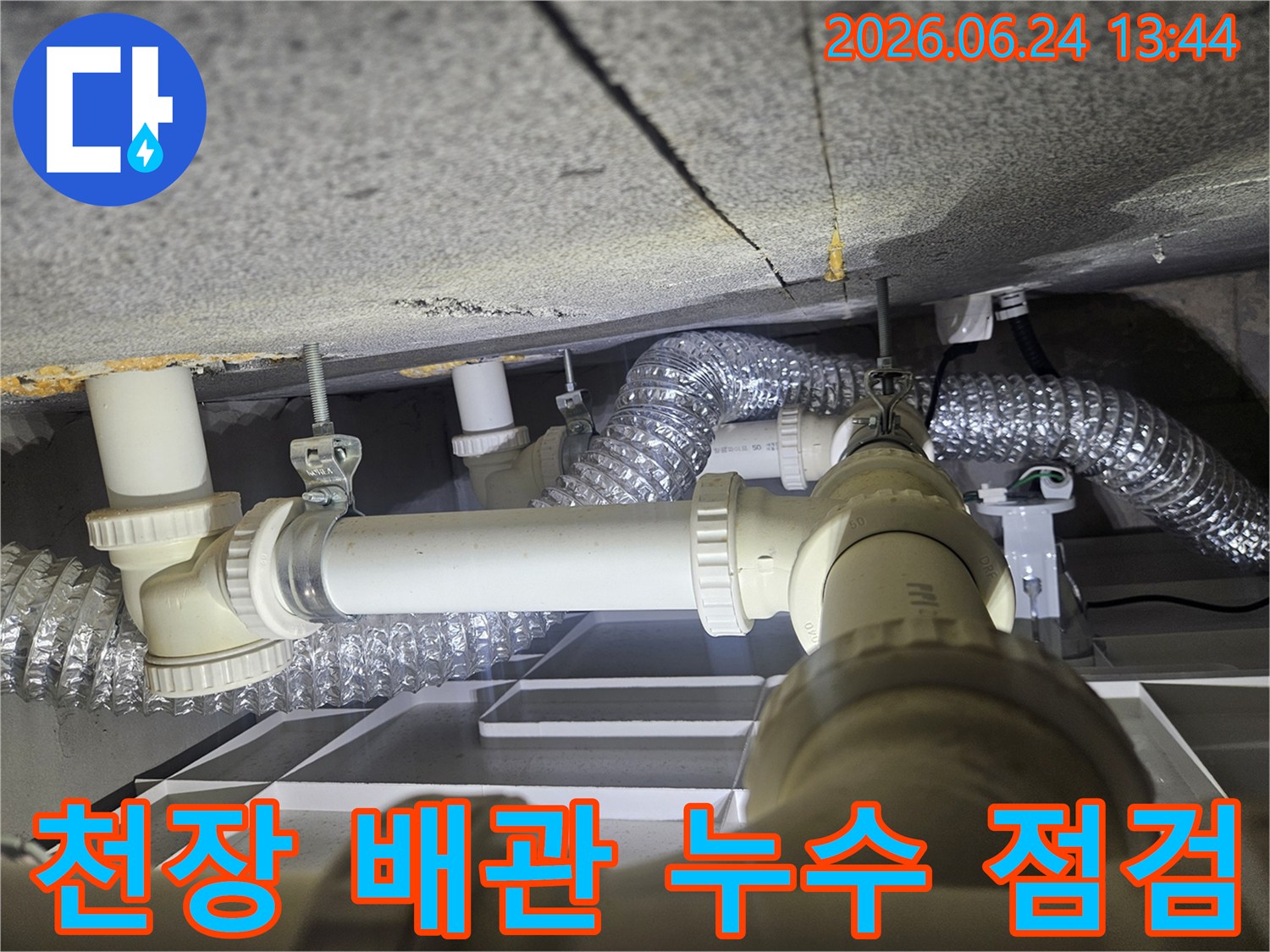 천장 내부의 복잡한 배관과-환기 덕트가-누수 원인을 찾기 위해-세심하게 점검되고 있습니다