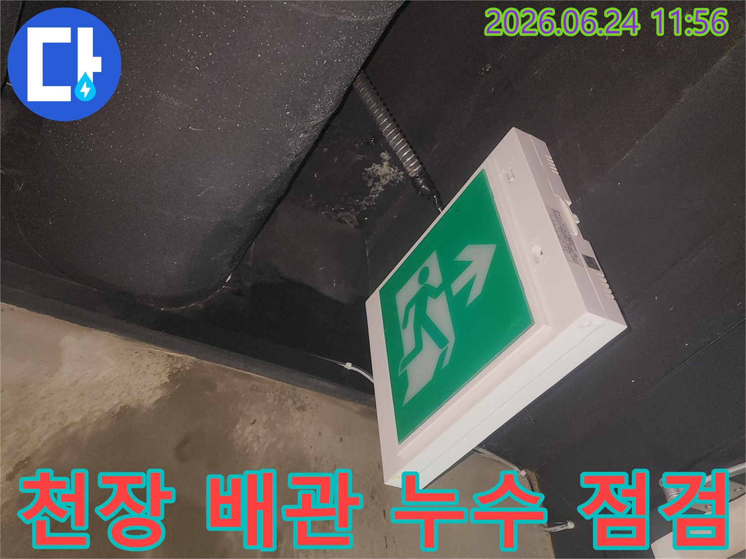 누수로 인해 젖어있는 천장과-비상구 표지판의 상태를 보여주는 사진입니다