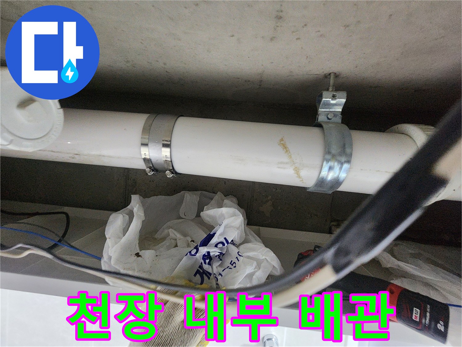천장 구조물에 설치된 흰색 배관과 고정용 금속 밴드입니다.
