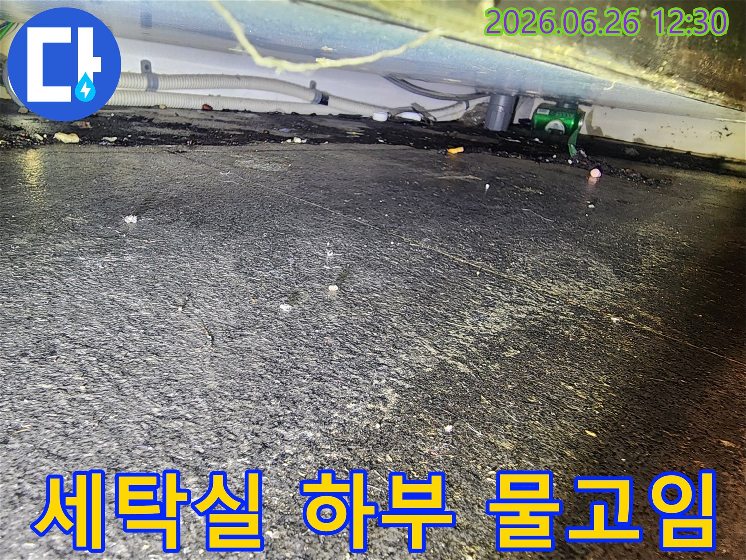 배관 연결부 근처-바닥에 고인 물과-흙먼지가 섞인-누수 현장을 촬영한 사진입니다