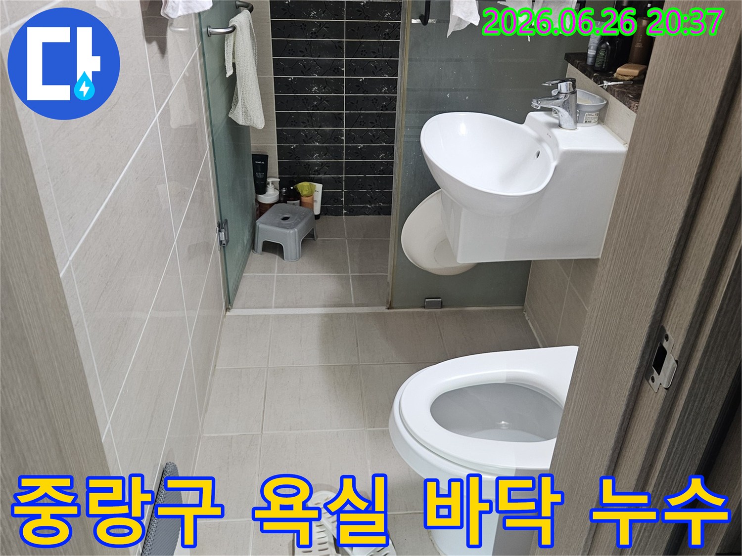 이 사진은-서울 중랑구의 한 욕실에서-바닥 누수 여부를-확인하기 위해-점검 중인 모습을 담고 있습니다-깨끗한 타일 바닥과-위생 도기들이 보입니다