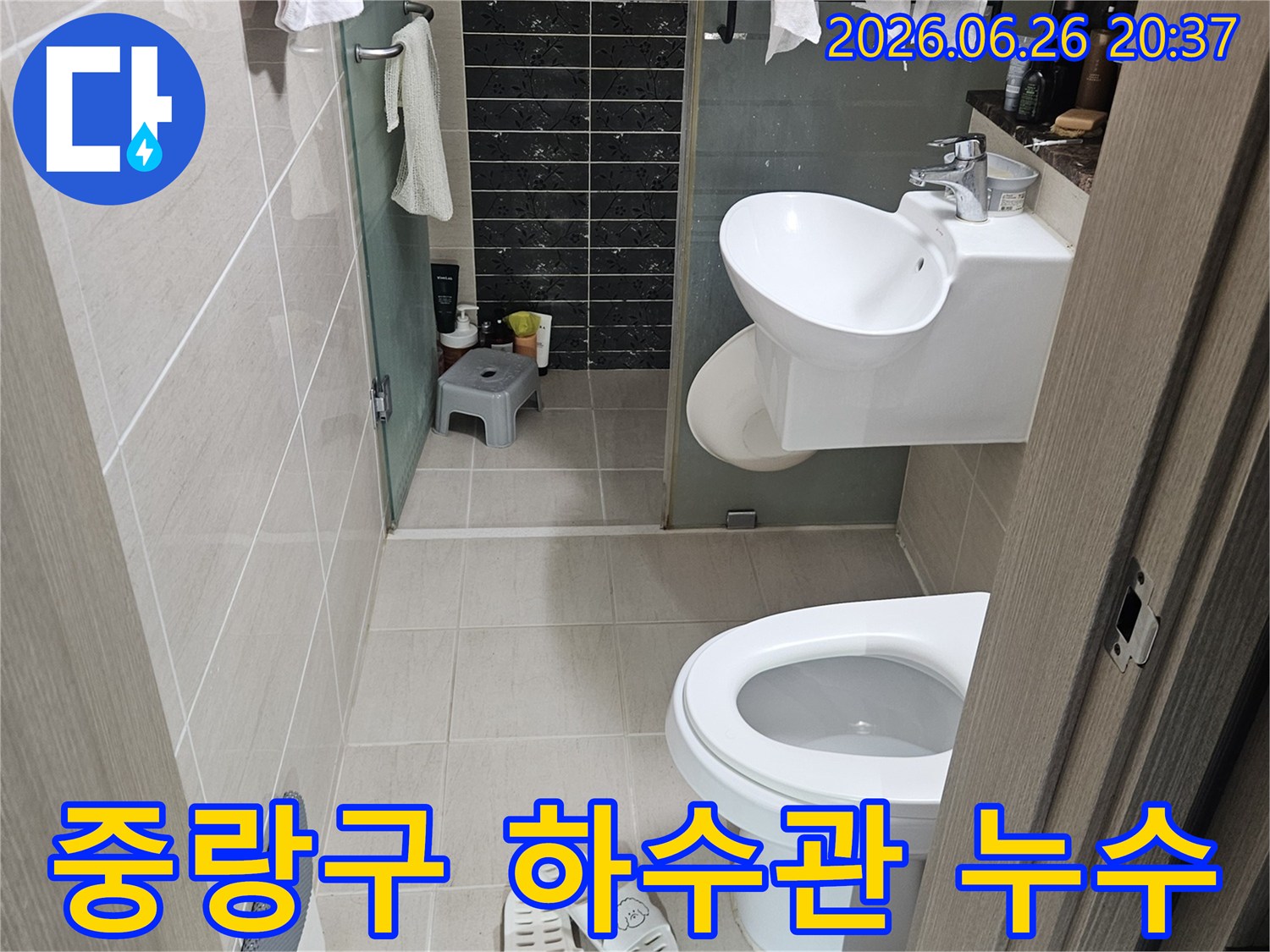 이 이미지는-서울 중랑구의 한 화장실에서-하수관 누수 여부를-확인하기 위해-점검 중인 모습을 담고 있습니다-변기와 세면대가 보입니다