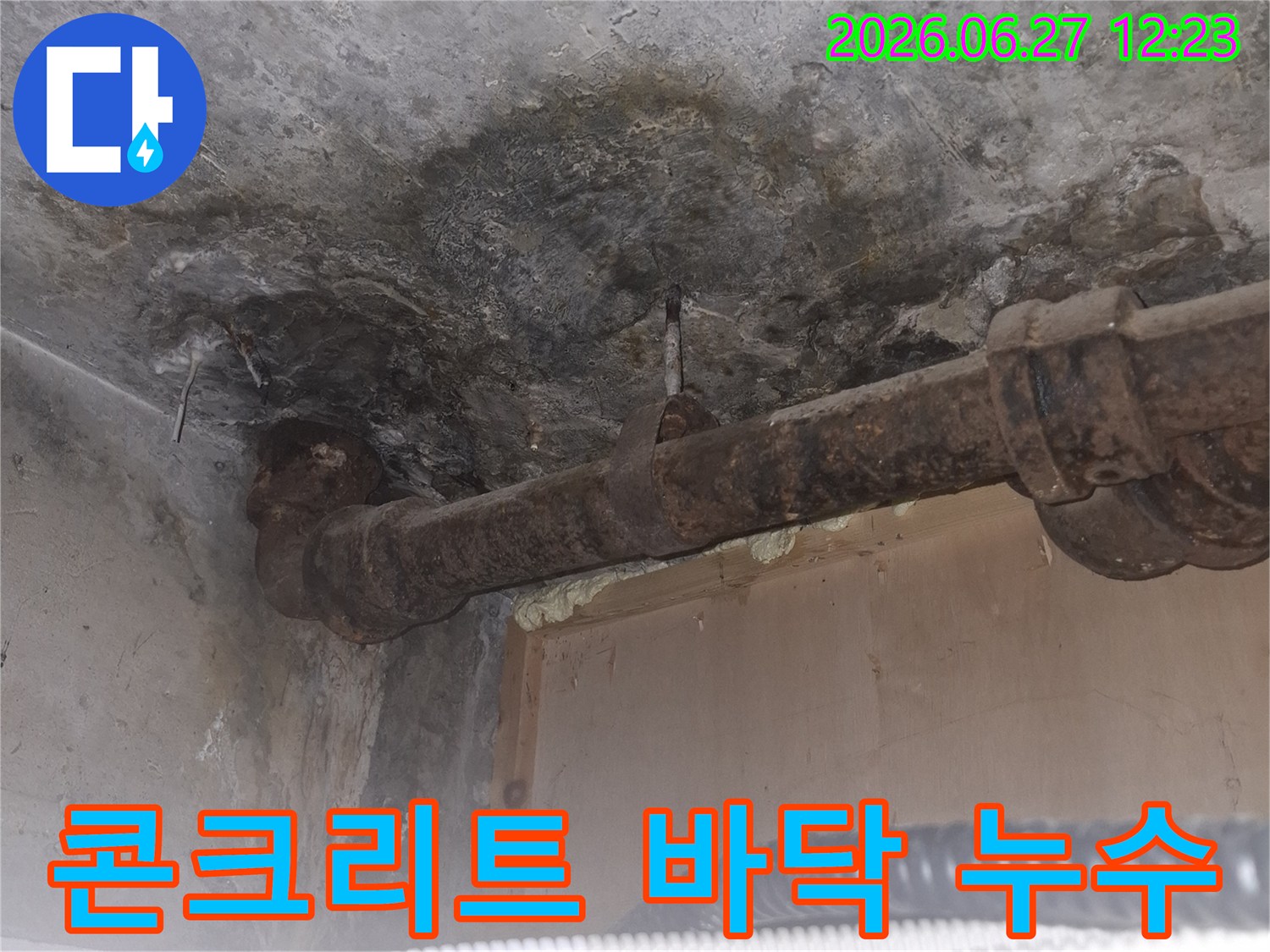 오래된 아파트의-콘크리트 바닥에서-발견된 누수 흔적과-심하게 부식된-금속 배관의-모습을 담은-현장 사진입니다