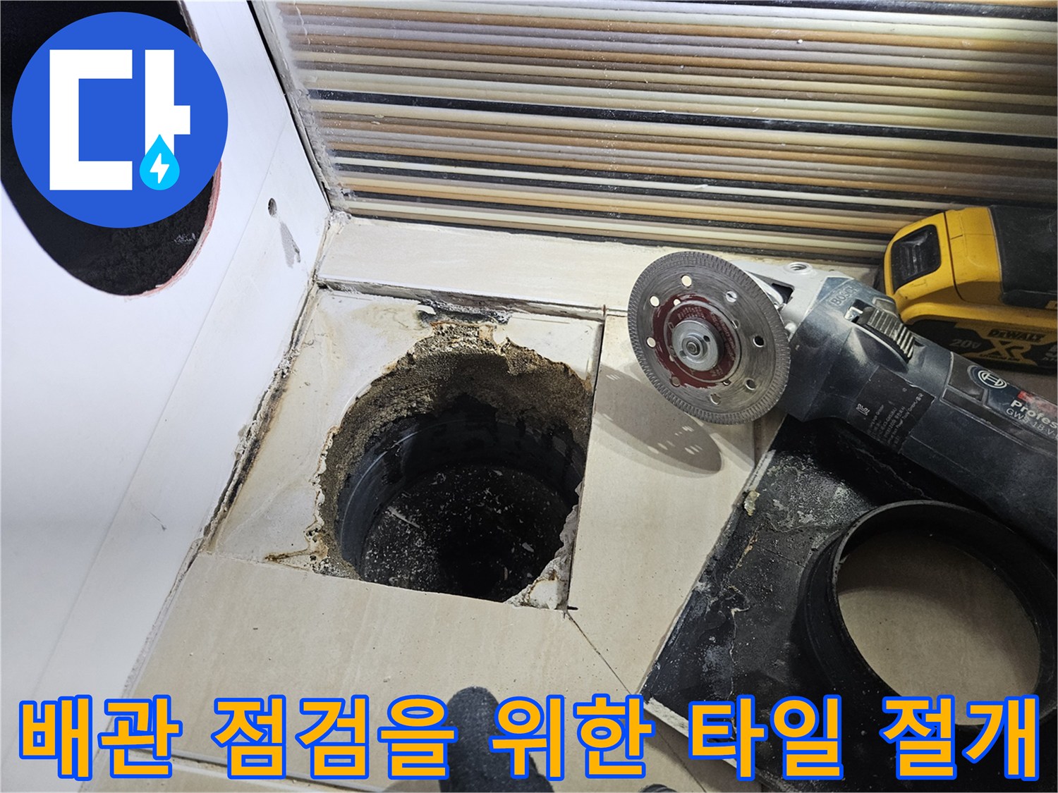 그라인더를 사용하여 욕조 옆면 타일을 제거하고 배관 노출을 시도하는 장면