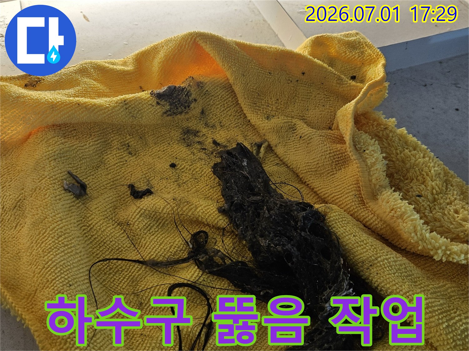 노란색 수건 위에 놓인-하수구 뚫음 작업으로 제거된-머리카락과 슬러지 덩어리입니다-이는 하수구 막힘의 주된 원인입니다