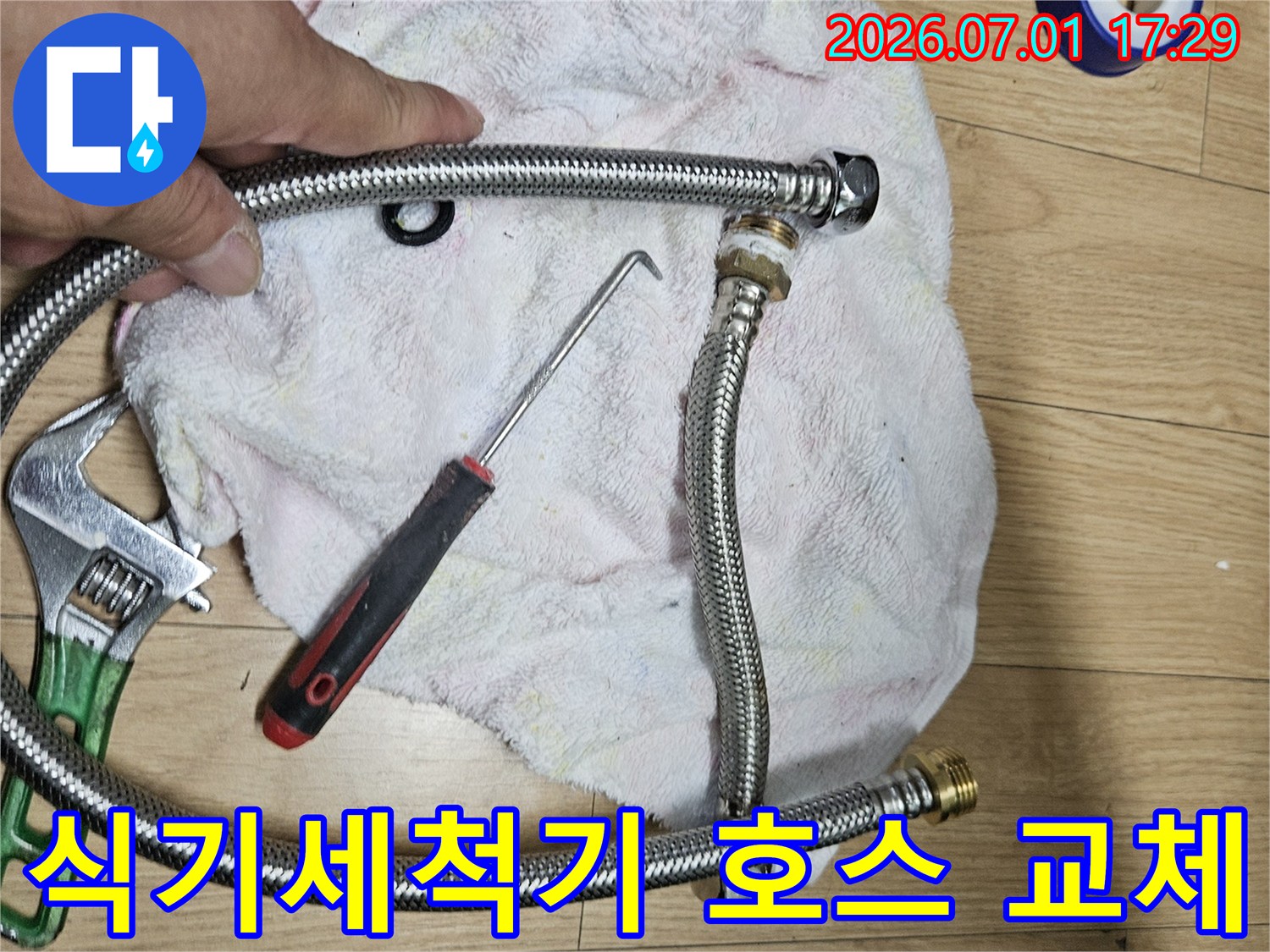 이 이미지는 빌라 주방 식기세척기 급수 호스 교체를 위한-새로운 호스와 작업 도구를 보여주는 현장 사진입니다