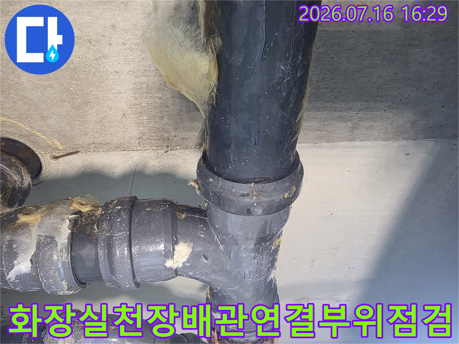 화장실 천장 내 노출된 배관 연결 부위의 누수 여부를 확인하는 장면