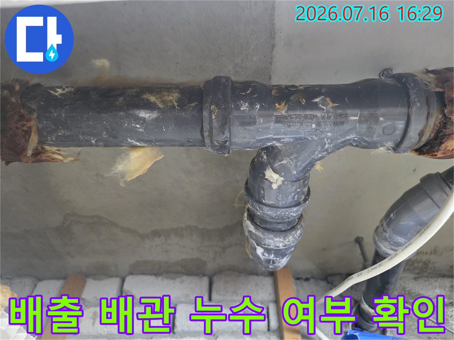 화장실 천장 내부의 배수 및 오수 배출 배관 연결부 상태를 세심하게 점검하는 현장 사진