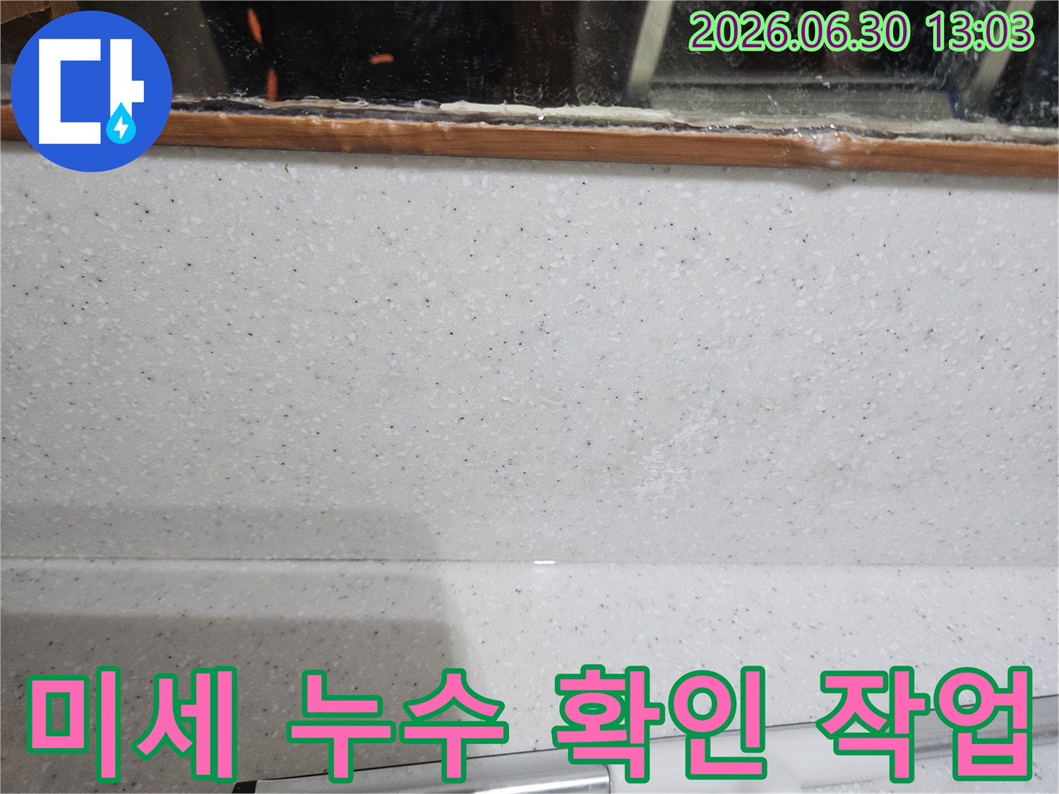 주방 싱크대-벽면과 상판 경계에서-발견된-희미한 물자국을-세밀하게 관찰하는 모습