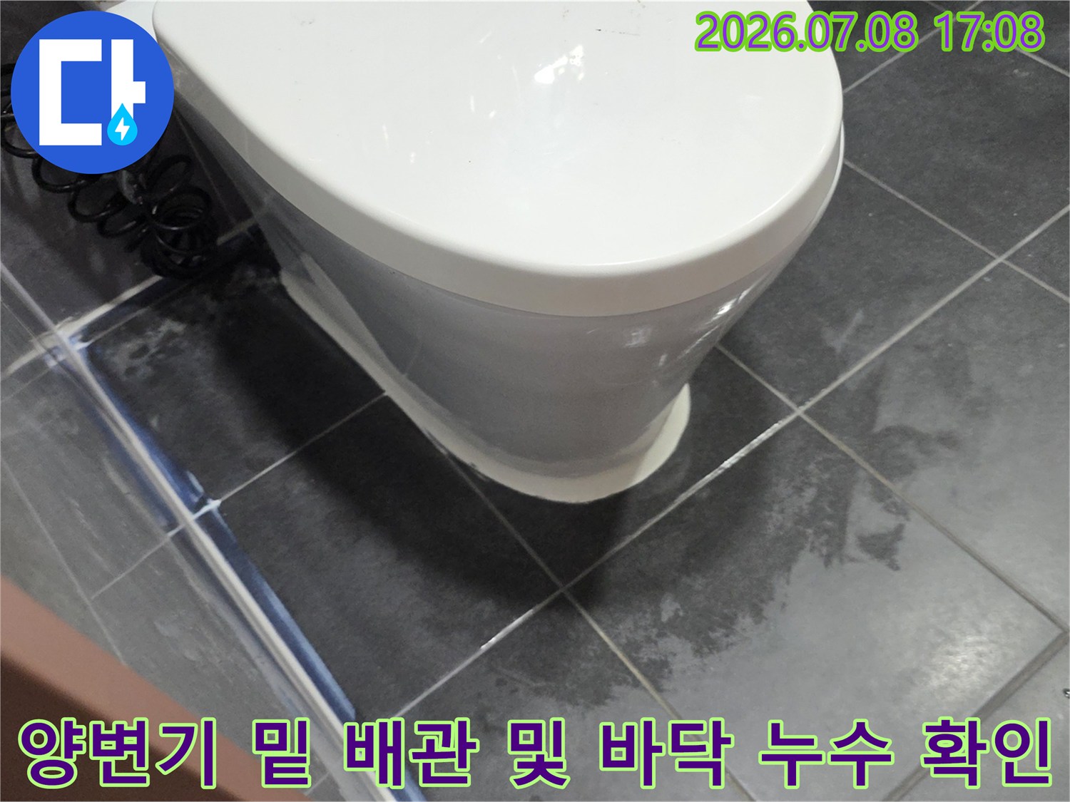 변기를 들어내어 노출된 하부 배관과 타일 사이의 수분 침투를 점검하는 장면