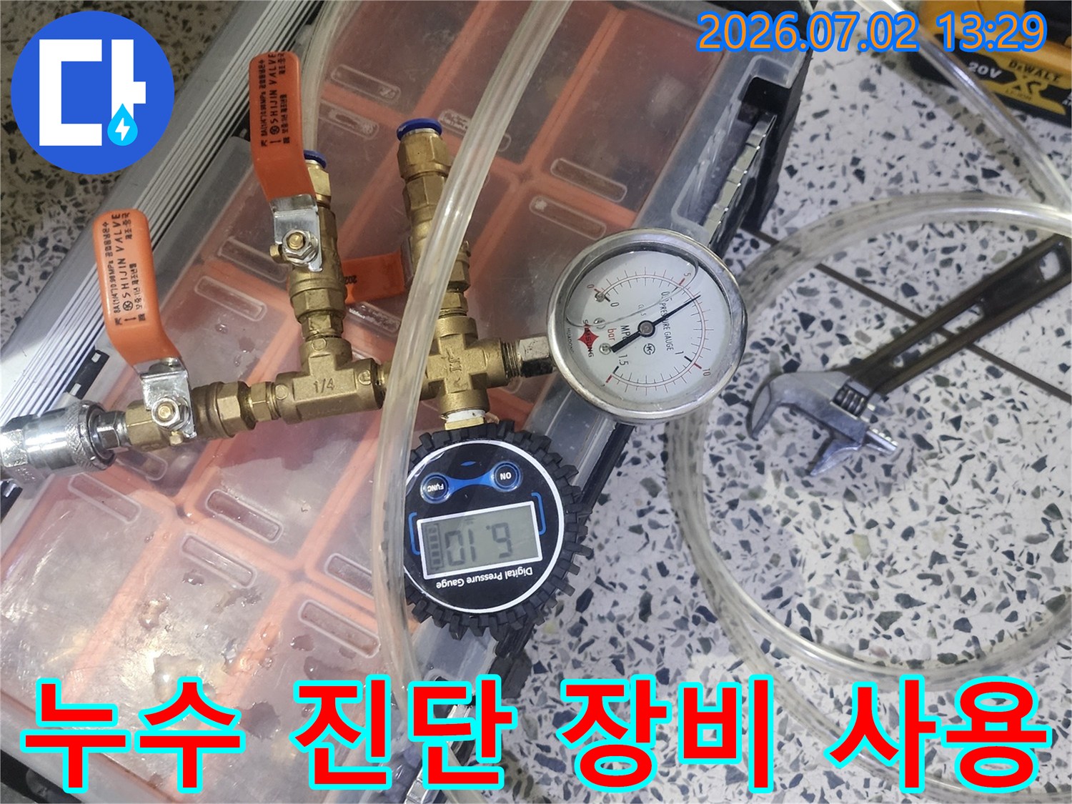 누수 탐지를 위해 압력 게이지와 밸브-튜브가 연결된 전문 장비를 사용하여 배관 압력을 측정하는 모습입니다
