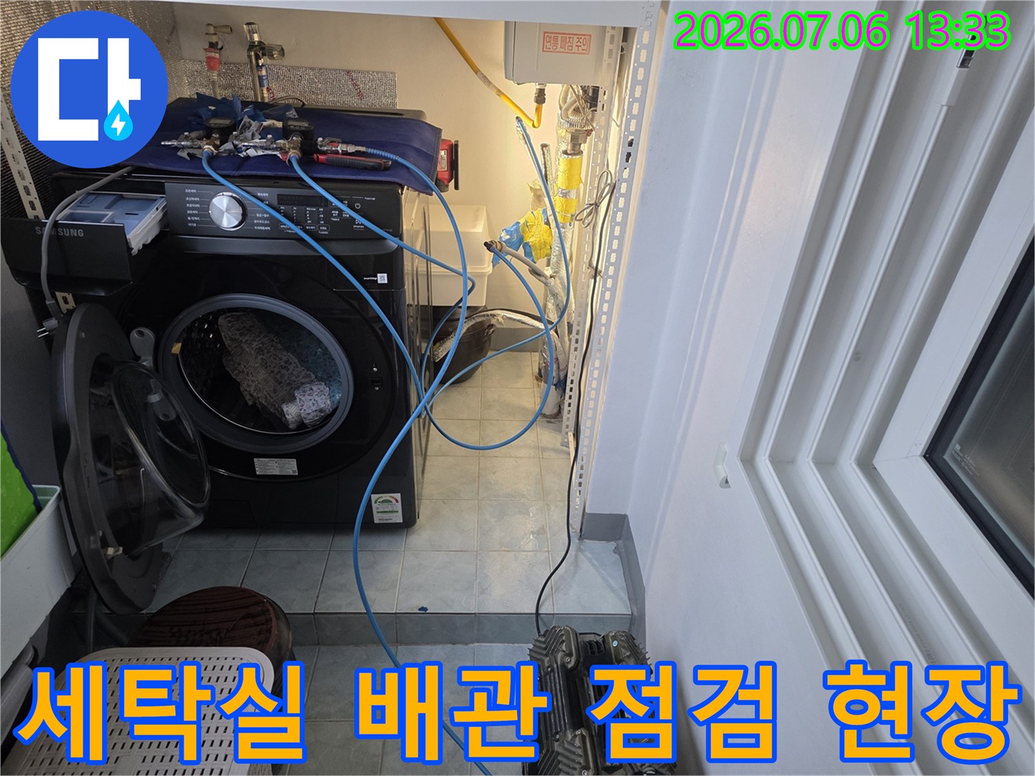 세탁기 옆으로 복잡하게 연결된 수도 배관과 계량기 주변을 점검하는 모습
