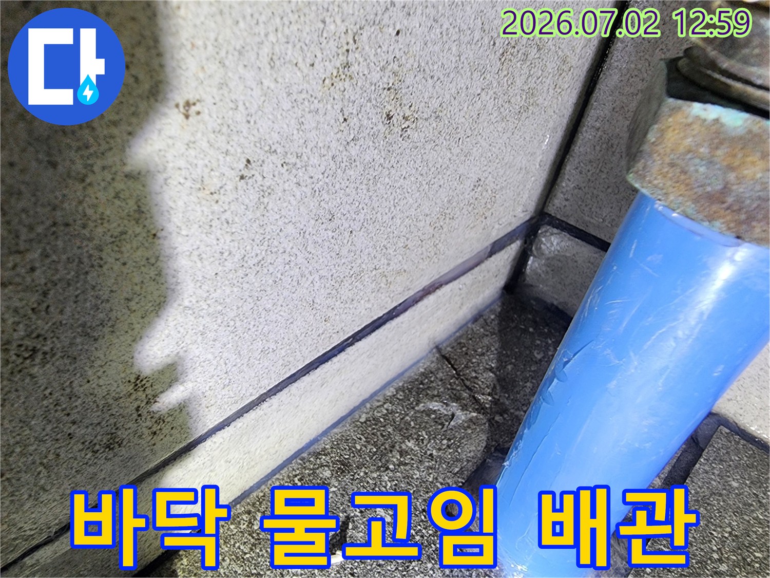 바닥에-물이-고여-있고-파란색-배관-주변에서-누수가-의심되는-현장을-누수-전문가가-점검하는-모습을-담은-사진