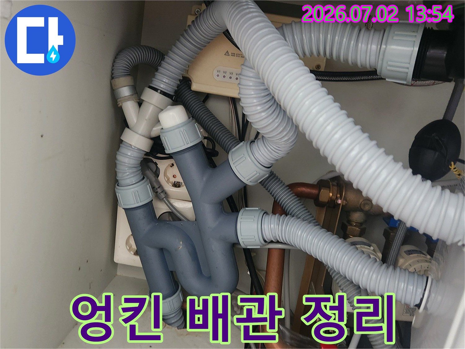 이 사진은-싱크대 하부의-복잡하게 얽혀있던-배수관들을-깔끔하게 정리하고-재설치하는-과정을 보여줍니다.