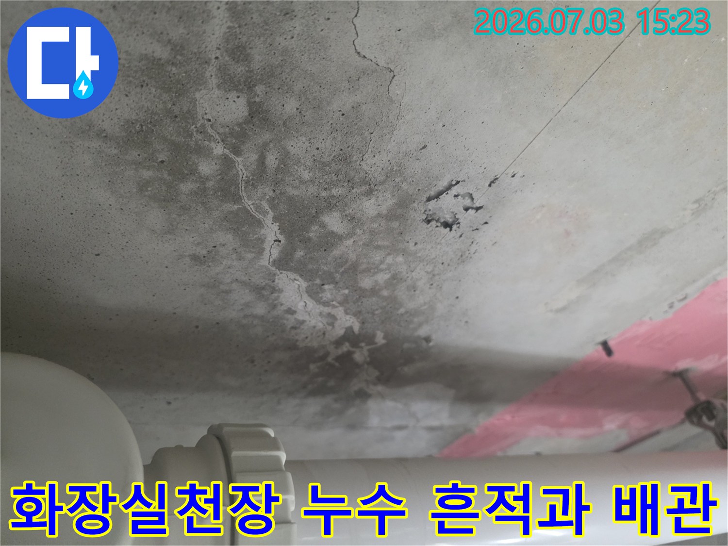 화장실 천장 콘크리트 면에 발생한 습기 얼룩과 균열 및 노출된 흰색 배관