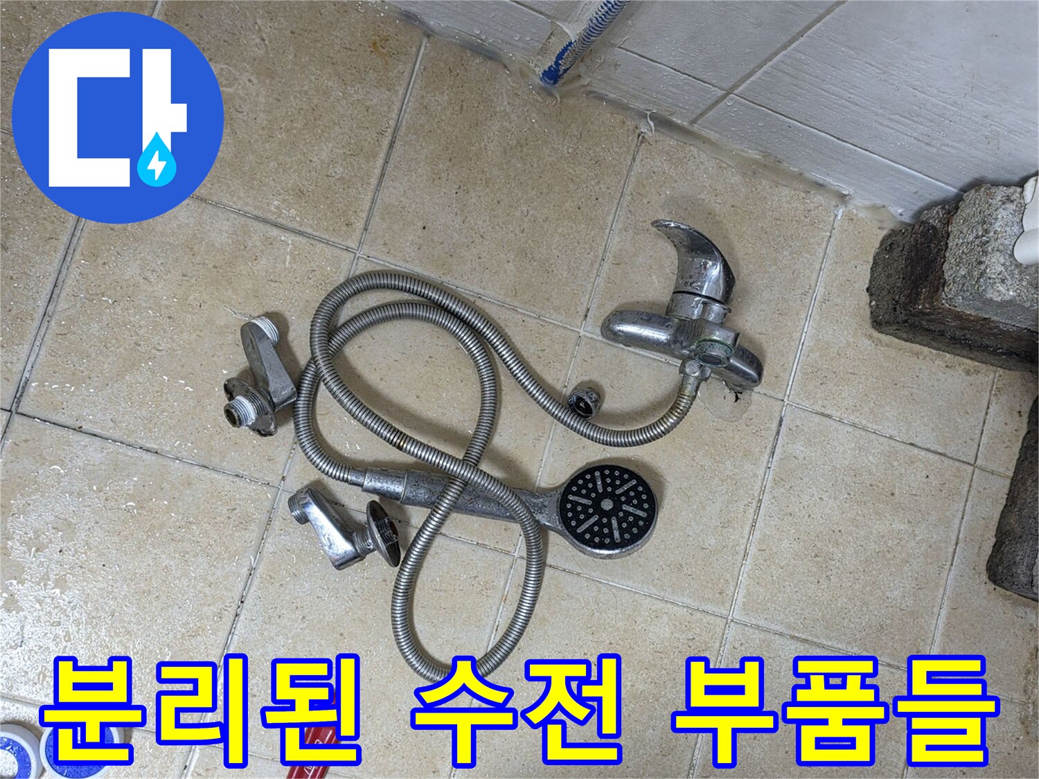 바닥 타일 위에 배치된-샤워기 헤드와 몽키스패너