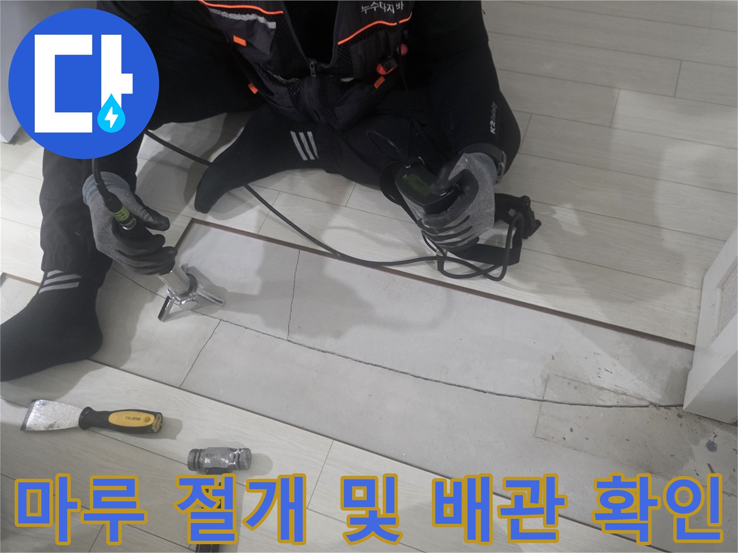 강마루를 일부 절개하고 전동 공구를 사용하여 배관 노출을 준비하는 모습입니다.