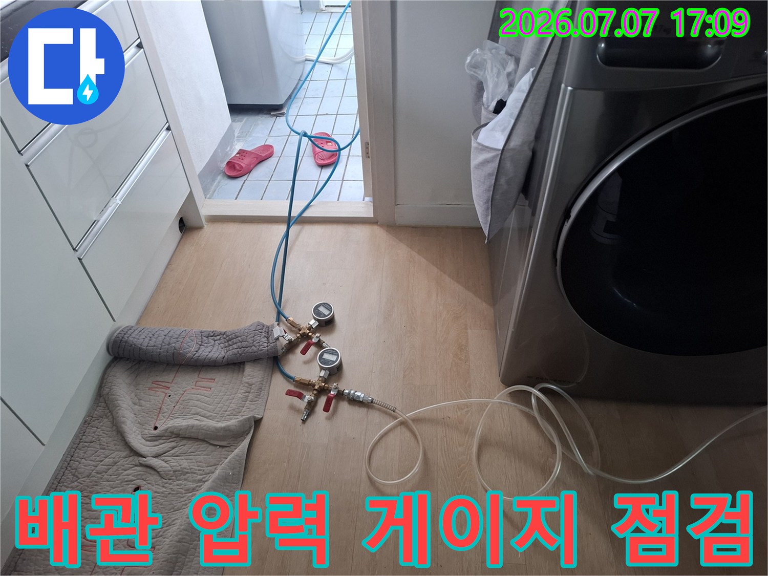 다용도실 배관에 연결된 여러 개의 호스와 측정 장비가 보이는 현장