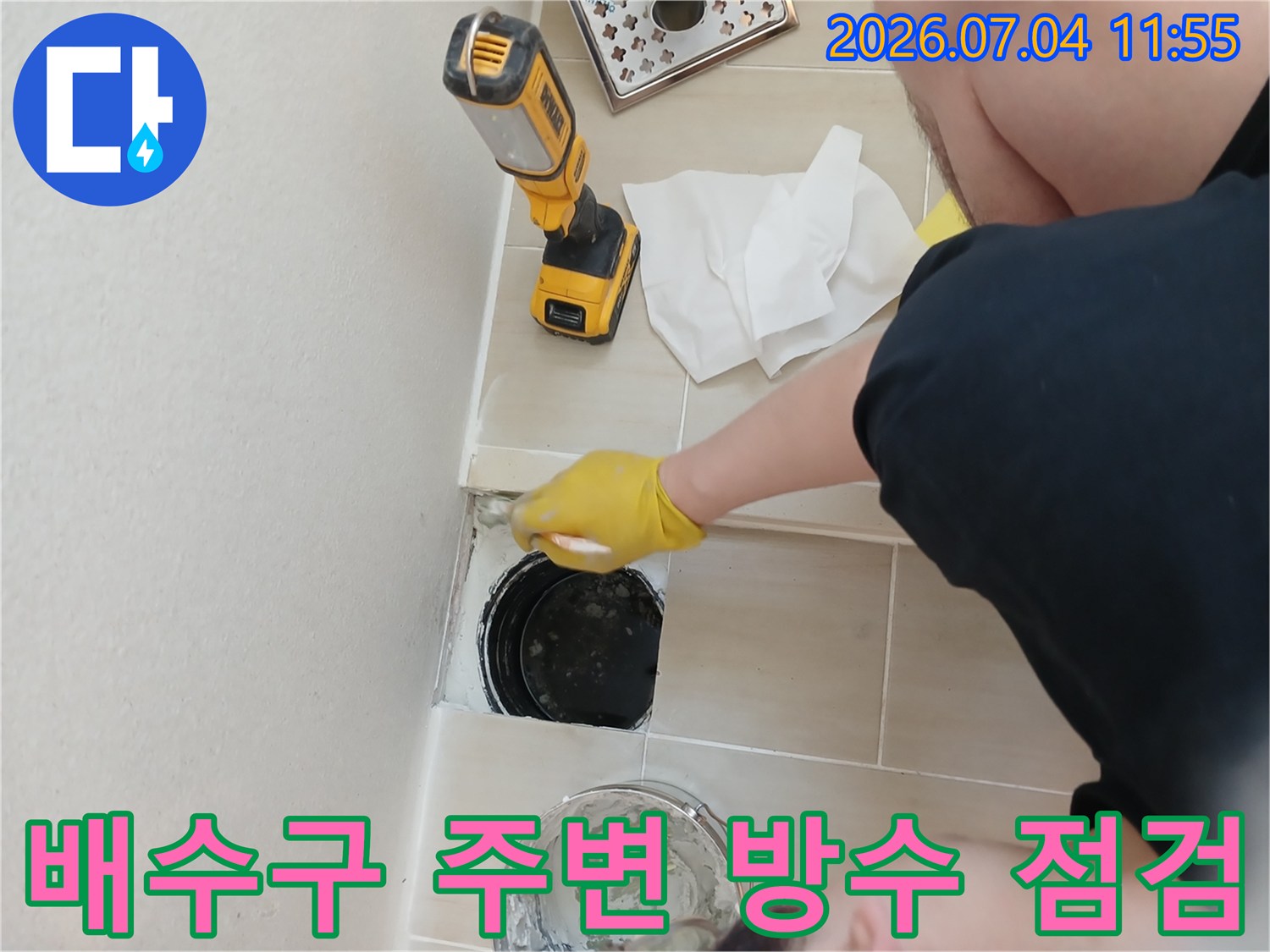 노란색 장갑을 착용한 작업자가 배수구 주변을 점검하는 모습
