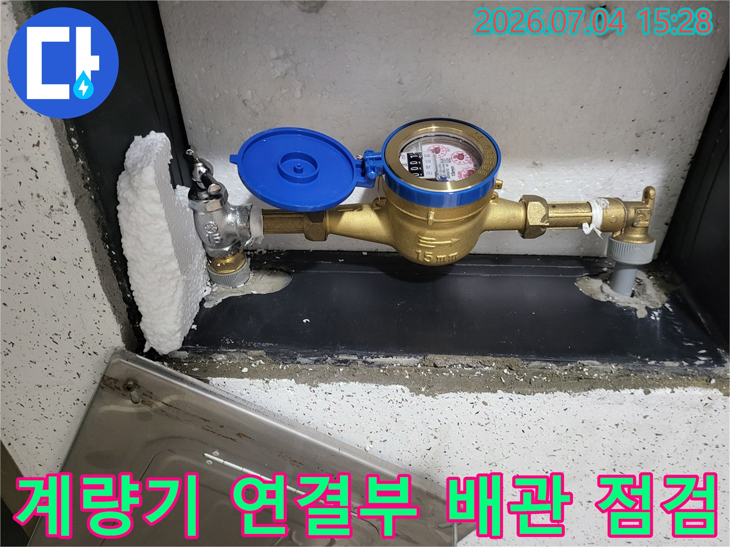 황동색 밸브와 파란색 계량기가 설치된 수도 함 내부