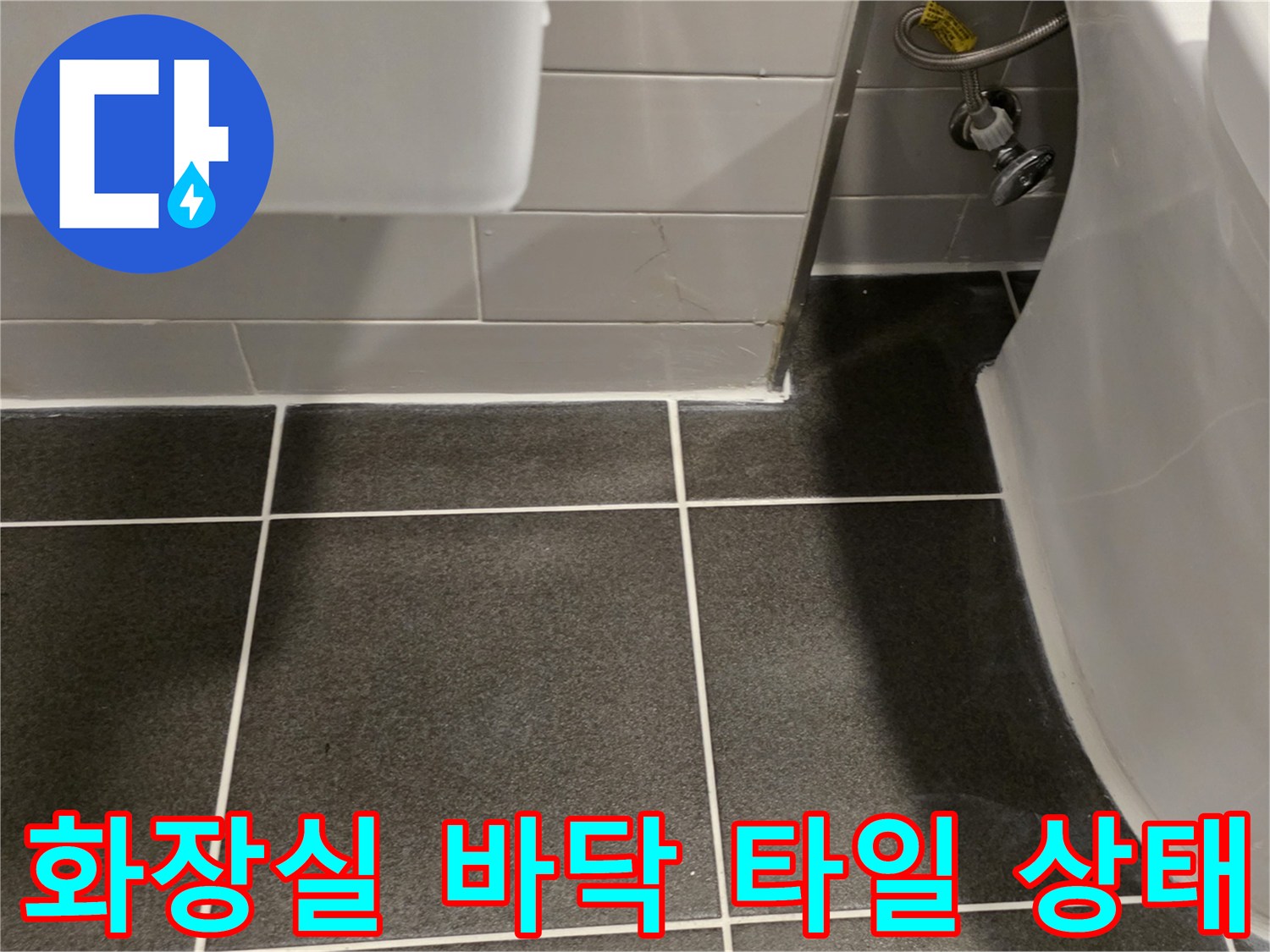 어두운색의 화장실 바닥 타일과 흰색 벽면 타일이 만나는 경계 부위