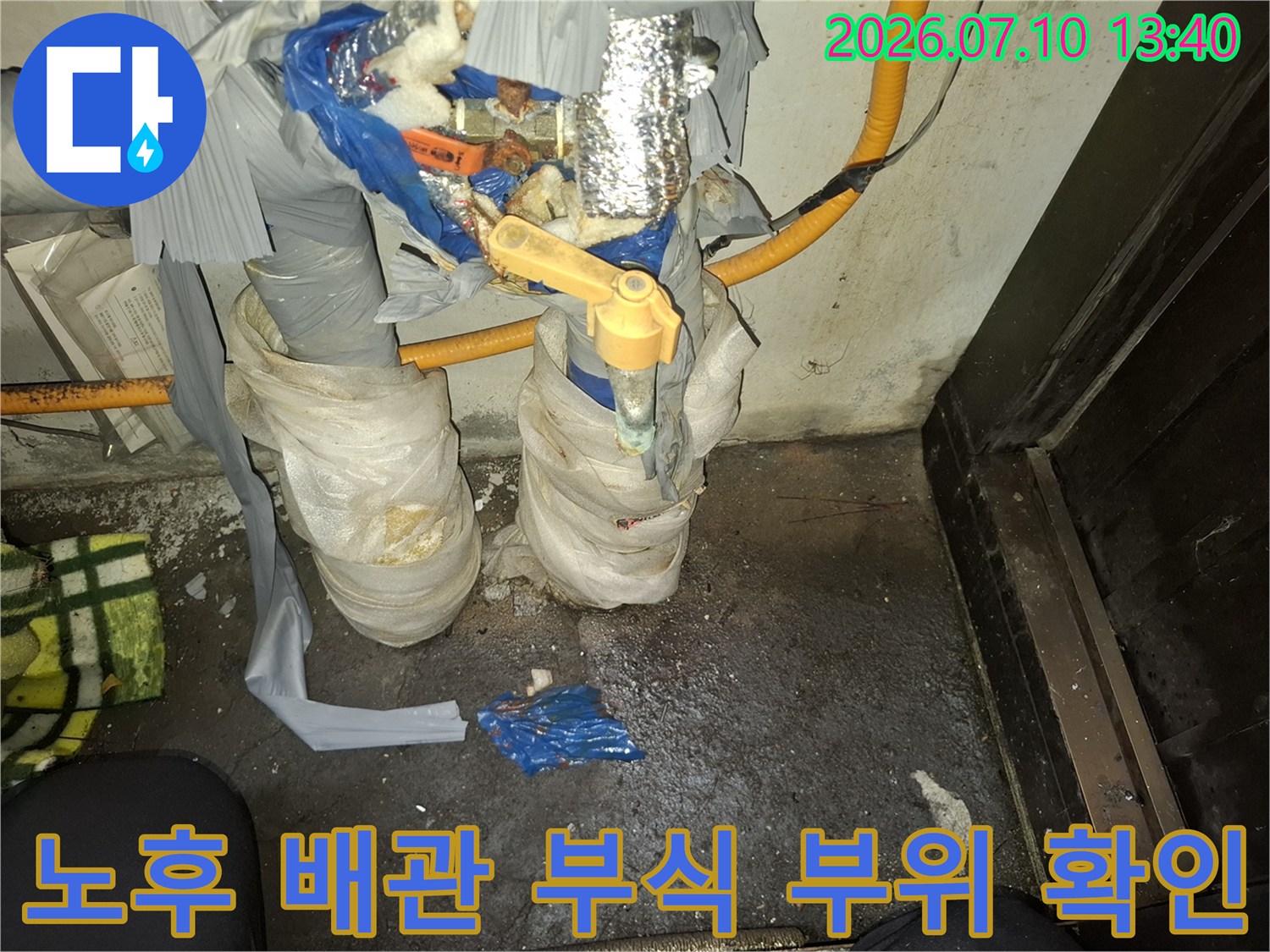 부식된 금속 파이프와 젖은 보온재로 감싸인 누수 현장 사진