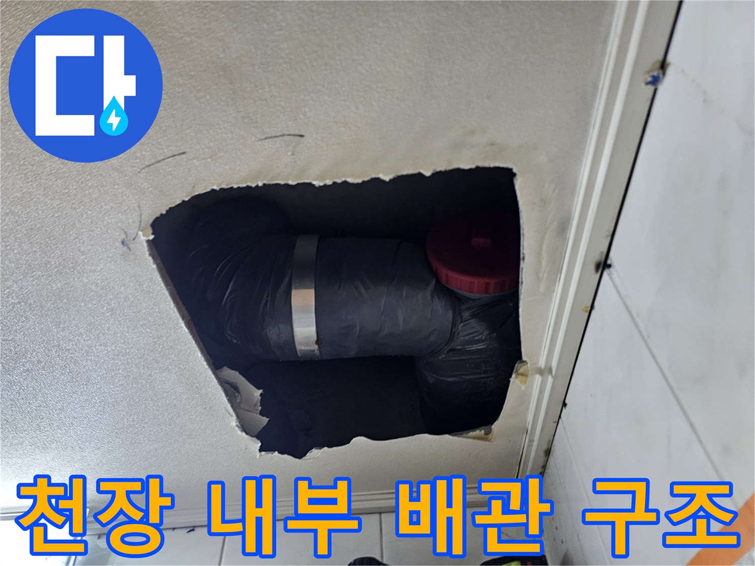 절개된 천장 안쪽의 보온 배관과 붉은색 마감 부품