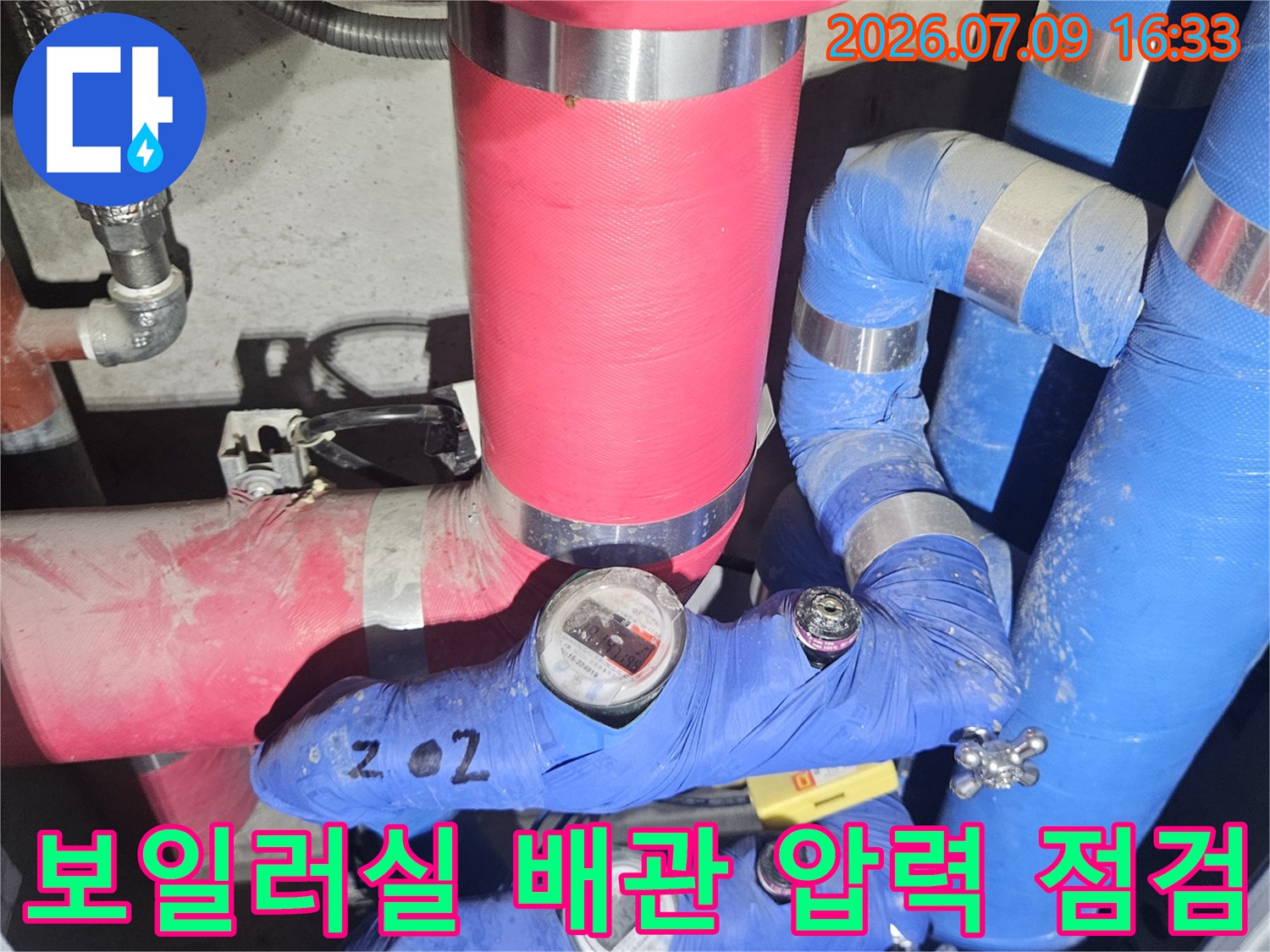 보일러실 온수 배관에 설치된 압력계와 파란색 보온재 마감 상태