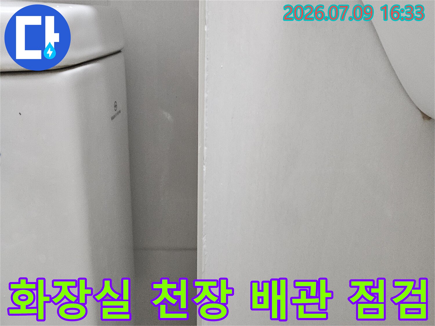 상단에 위치한 화장실 천장 내부의 흰색 마감재와 노출된 부속품 구조
