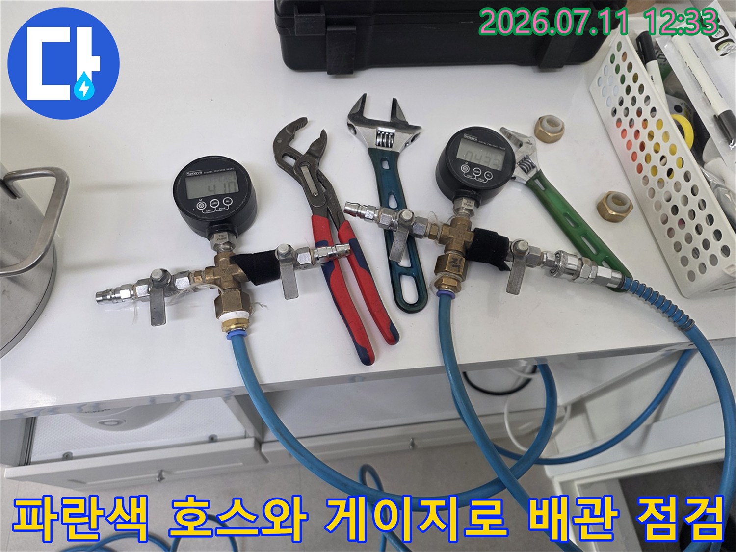 멀티미터 형태의 압력계와 파란색 호스가 연결된 공압 테스트 장비 현장 사진