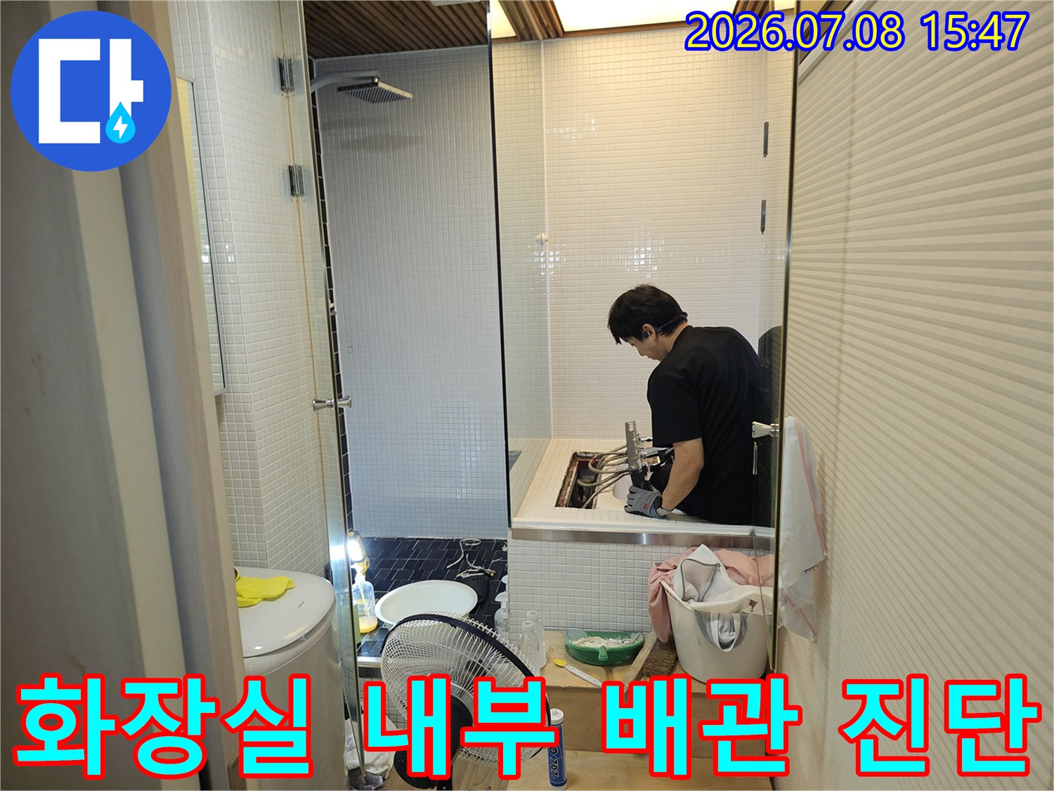 작업자가 화장실 세면대 하부 공간에서 정밀 점검을 수행하는 모습