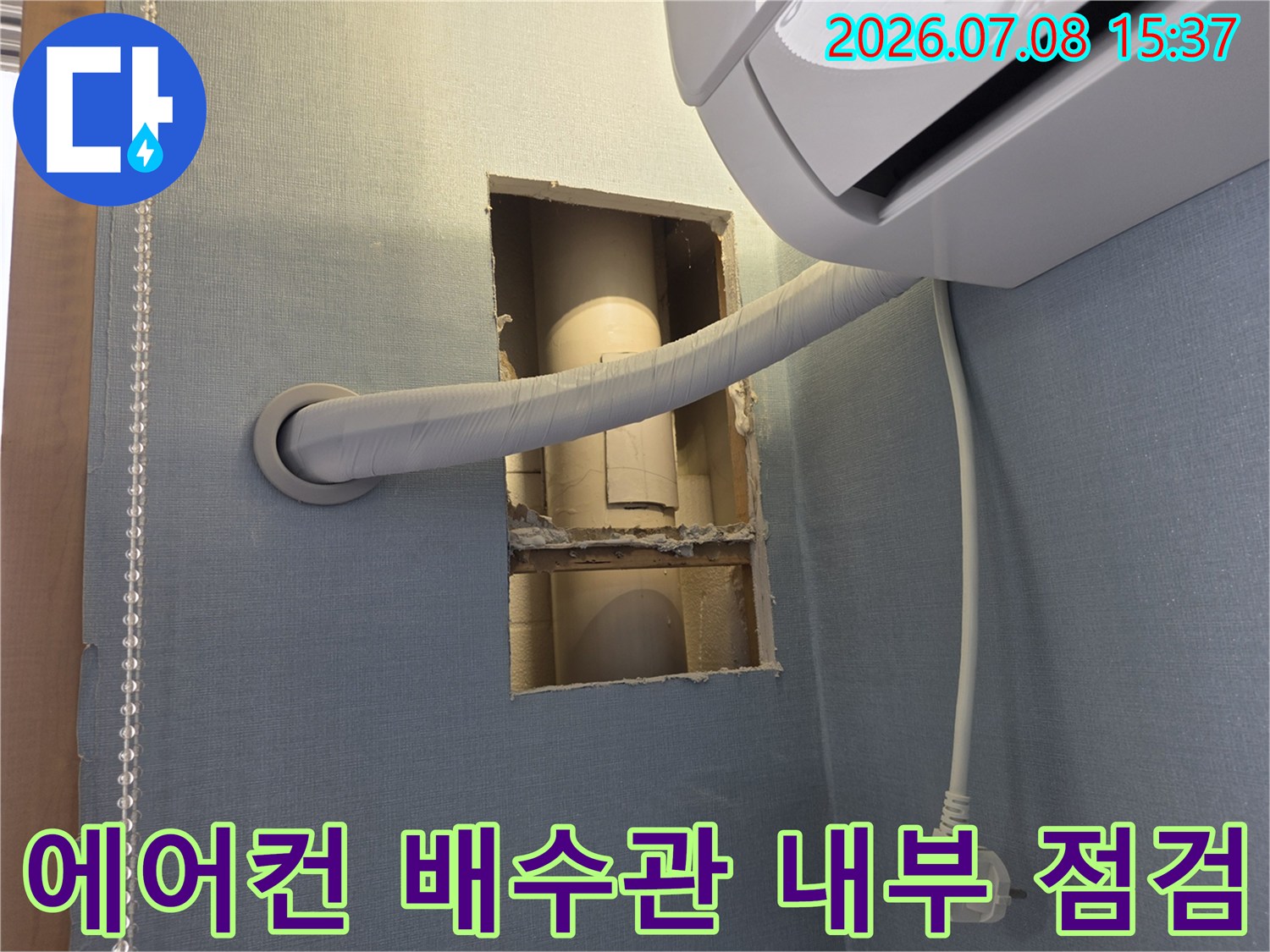벽체를 절개하여 노출된 에어컨 배수용 드레인 호스의 연결 부위 상태를 확인하는 모습