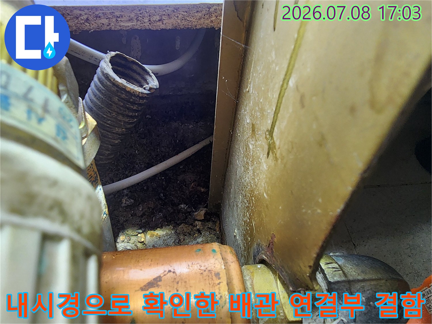 어두운 공간 속 노출된 수도 배관과 누수 흔적이 있는 연결 부위