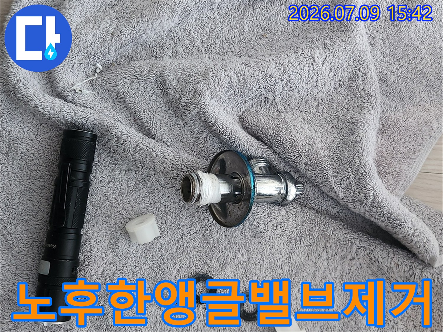탈거된 변기 부속품과 앵글밸브를 수건 위에 나열하여 점검하는 장면
