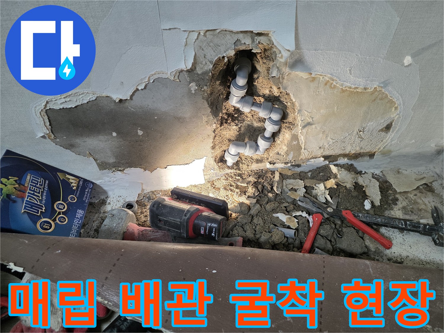 벽면 내부의 회색 배관과 주변 젖은 토사 및 작업 장비