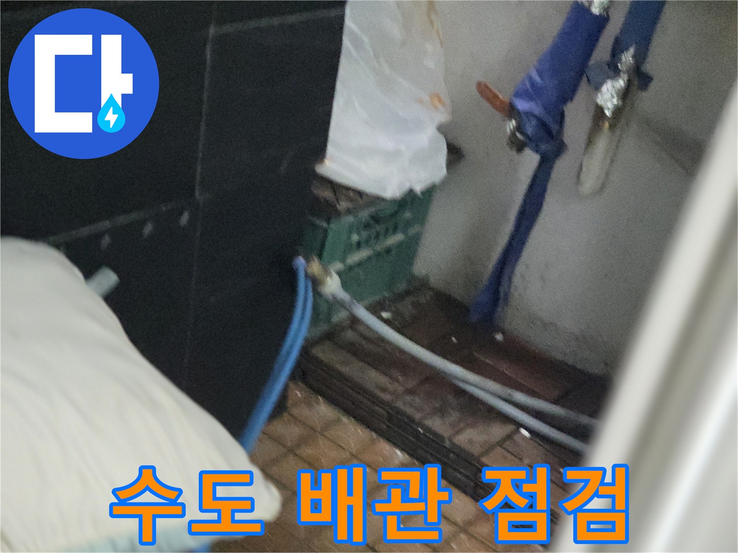 벽면에 연결된 파란색 호스와 노출된 부속품 근처의 누수 흔적