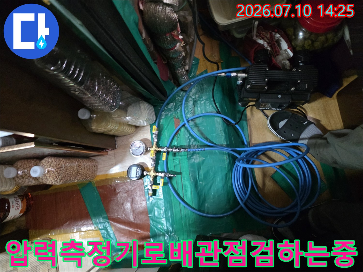 디지털 압력 게이지와 파란색 호스를 연결하여 배관 누수를 정밀하게 점검하는 현장 모습