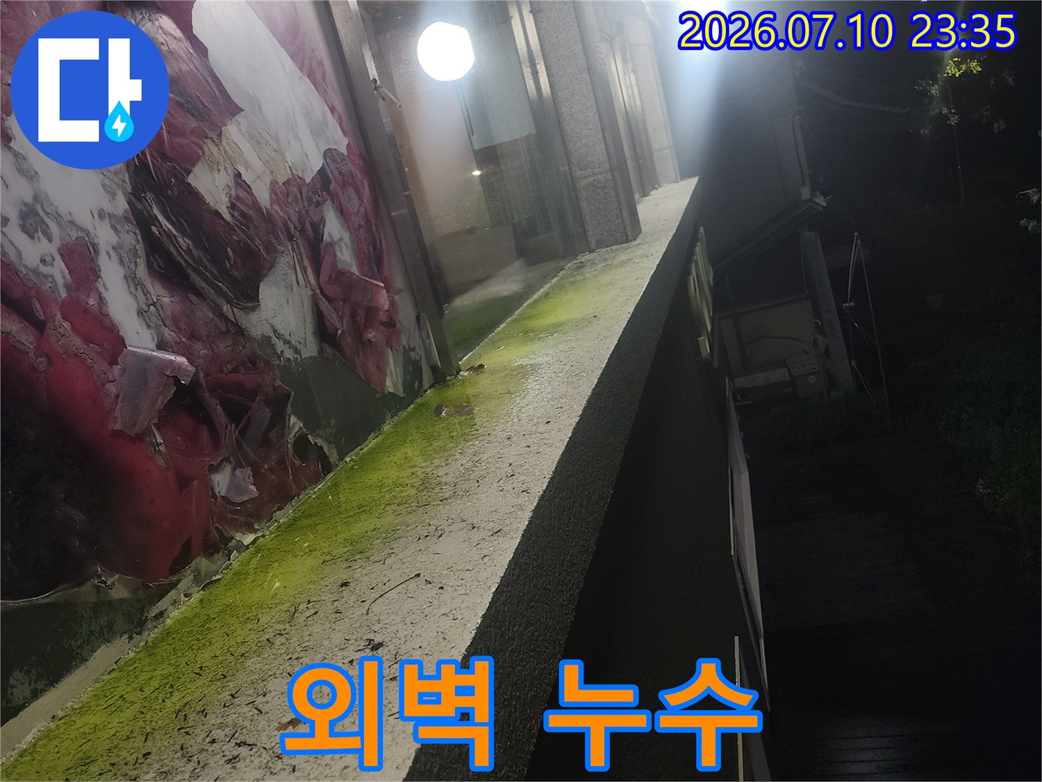 건물 외벽에서 누수가 의심되는 상태를 보여줍니다. 건물 외벽에 습기가 묻어 있고, 일부 곰팡이가 발생한 것을 확인할 수 있습니다.