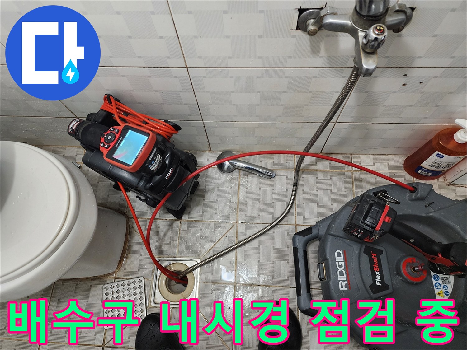 화장실 배수구 주변에 내시경 카메라와 장비를 배치하여 하수관 내부 상태를 확인하는 모습입니다.