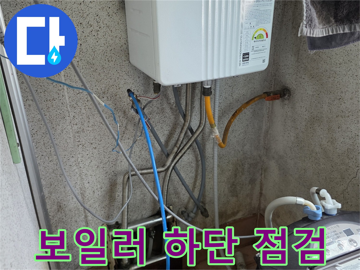 보일러 아래 배관 연결 부위와 압력 측정용 파란 호스