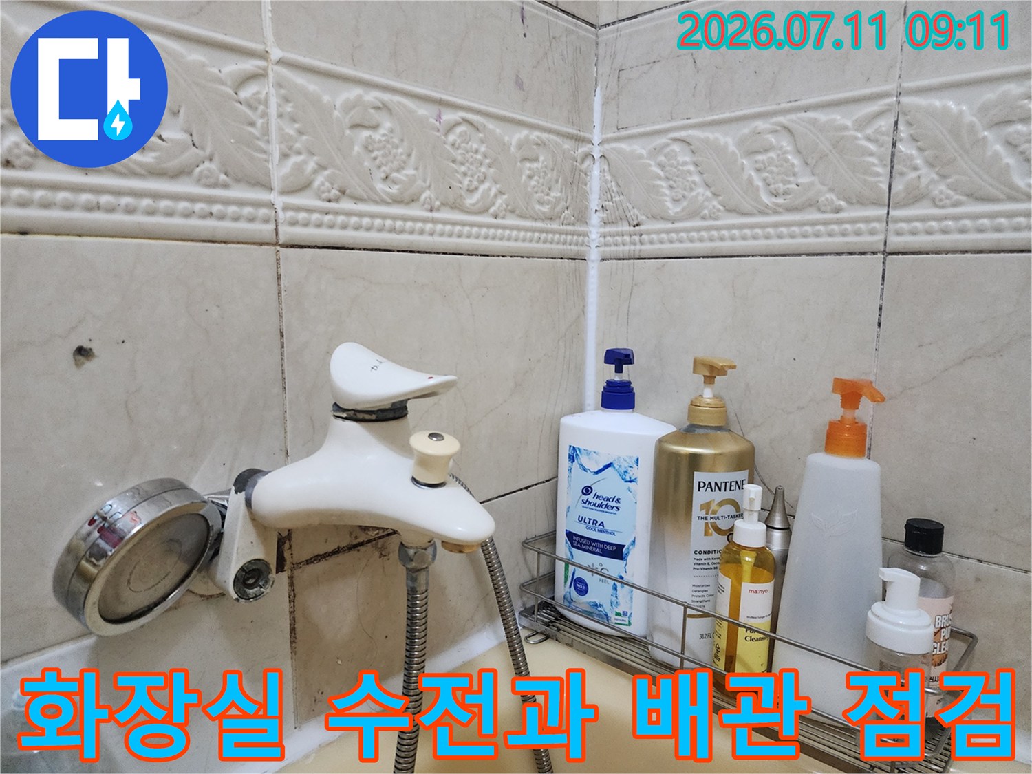 세면대 아래 위치한 흰색 수도꼭지와 주변 배관의 상태를 점검하는 모습