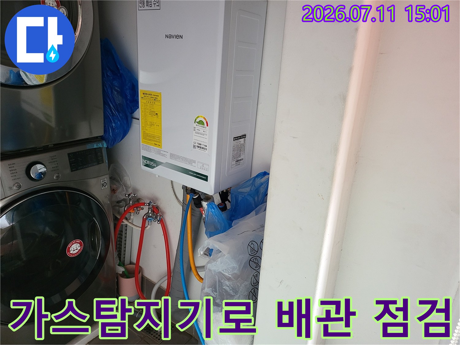 세탁기 옆 온수기 배관을 가스로 검사하는 모습