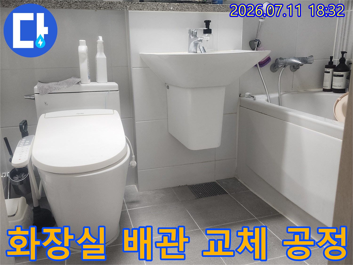 변기 옆 공간에 위치한 수도 배관을 점검하고 수리하는 장면