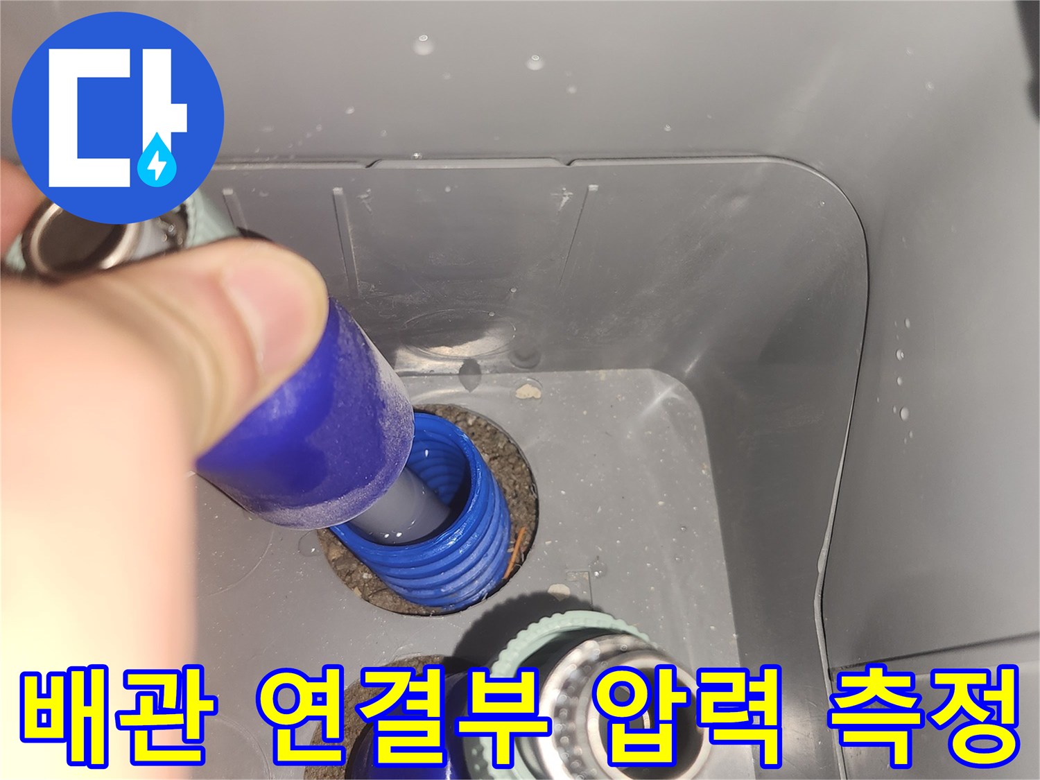 파란색 배관 부속에-공압계를 연결하여 누수 여부를 판단하는 장면