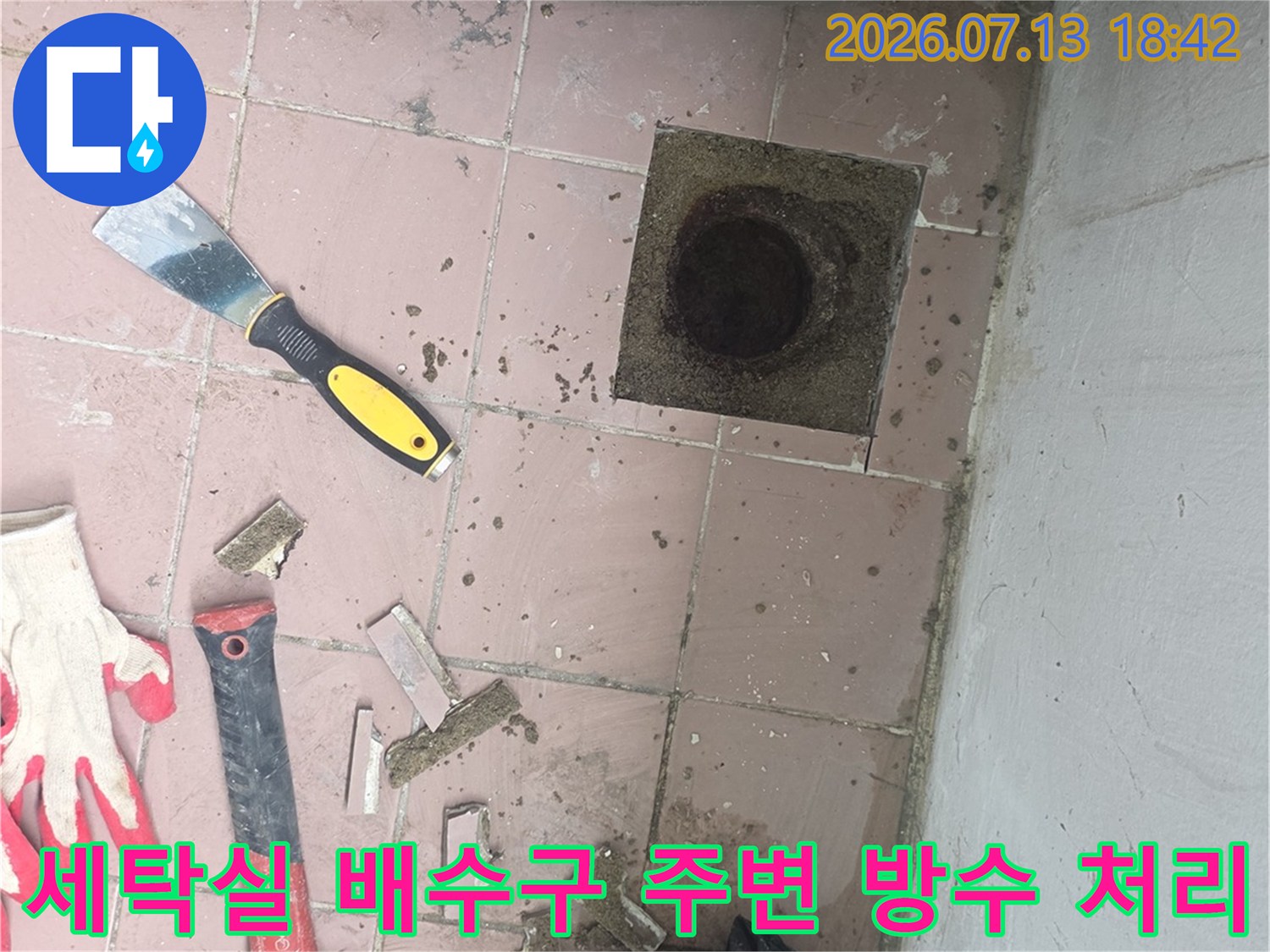 세탁실 바닥의 노출된 배수 트랩과 파손 부위를 정밀하게 보완하는 공사 현장 사진