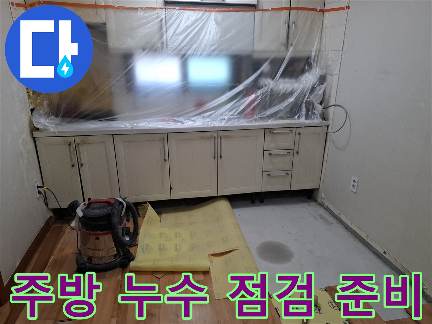 싱크대 아래 비닐 보양과 청소 장비가 놓인 주방 현장