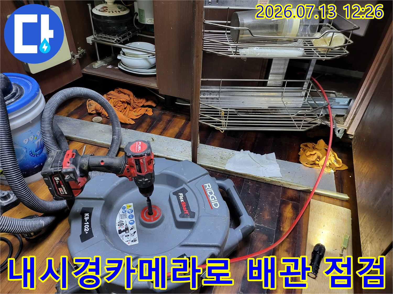 싱크대 아래 공간에서 내시경 장비와 석션기를 이용해 배수관을 정밀하게 점검하는 모습